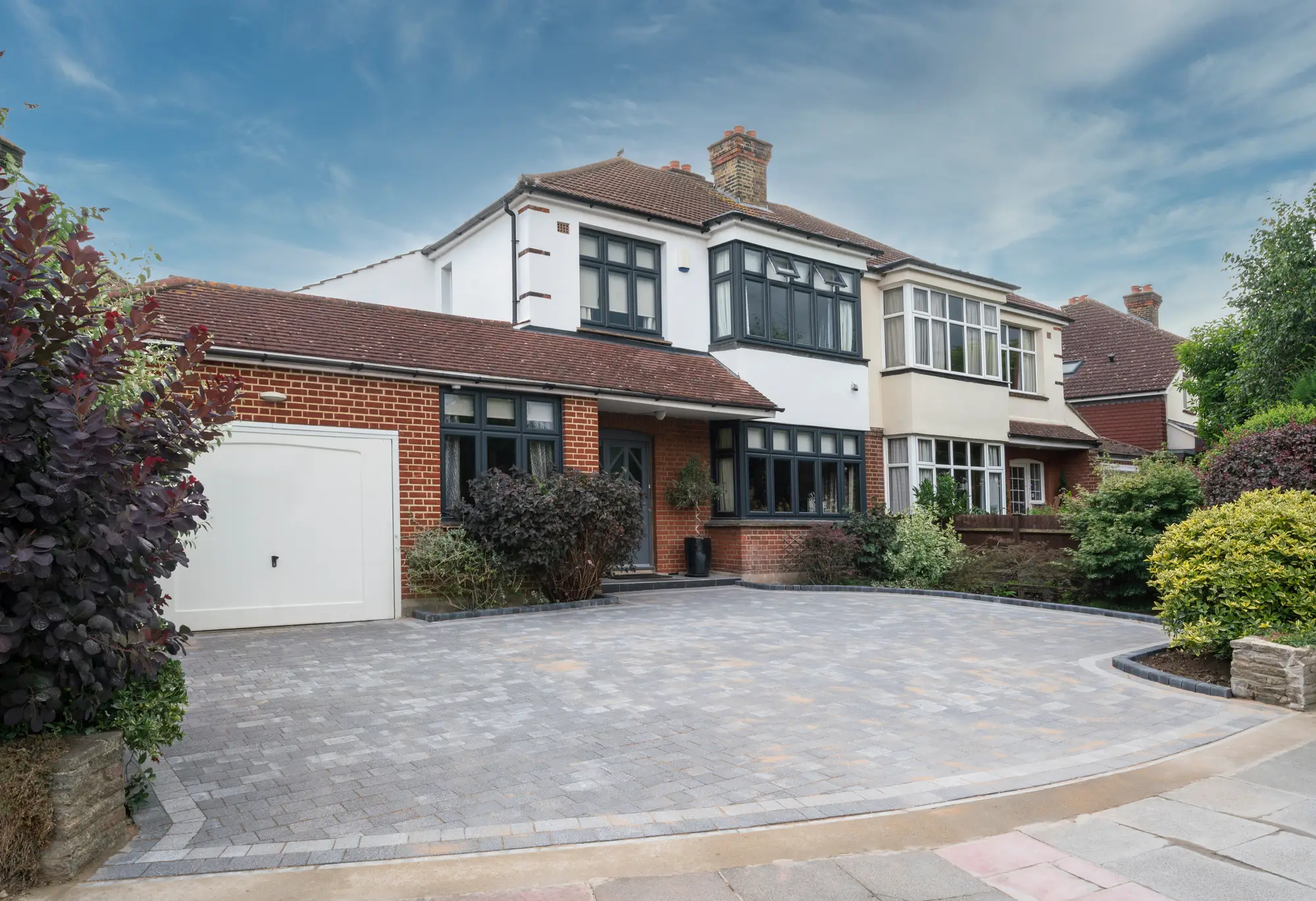 Grey block paved driveway sweeping in front of a semi-detached house