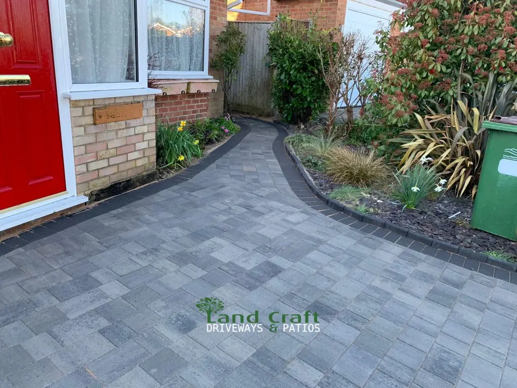 Grey block paving curving past a red front door