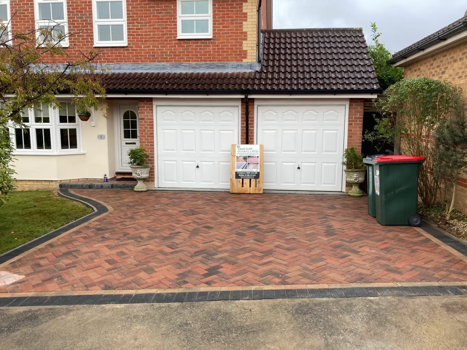 Red block paved driveway with a charcoal border and double garage