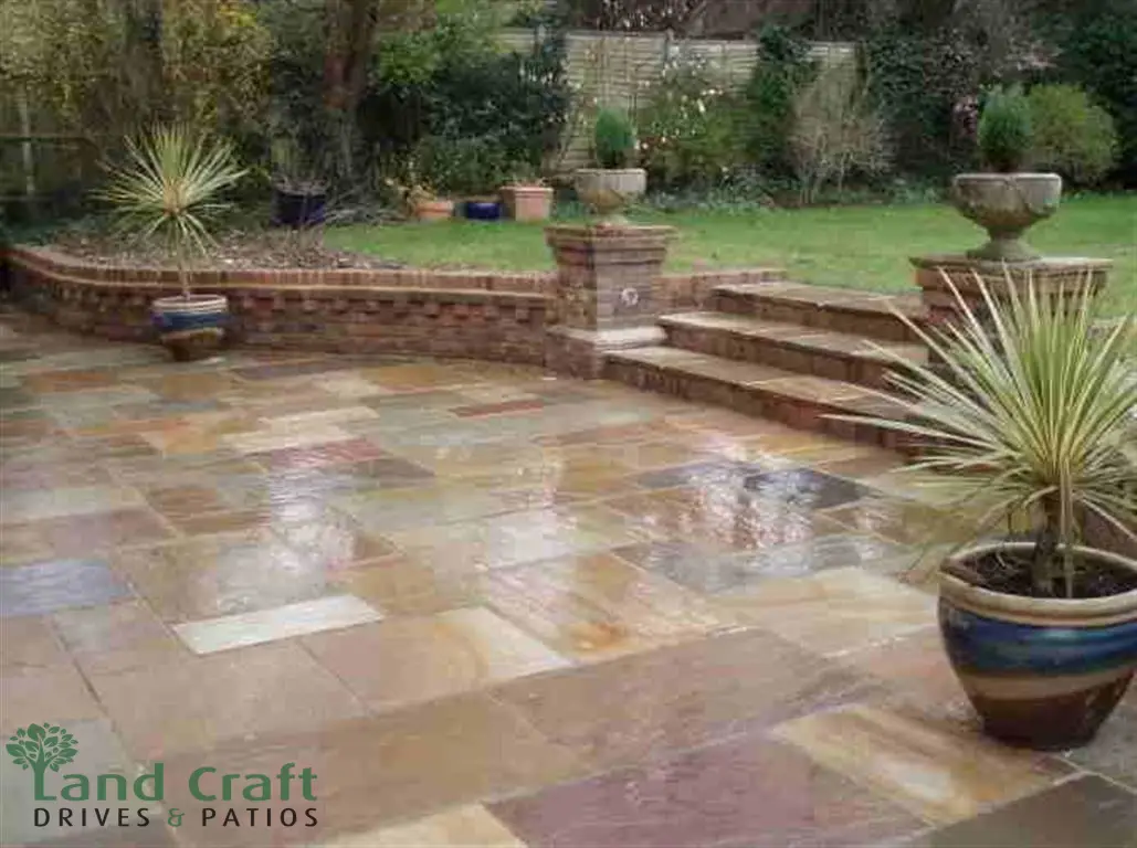 Sandstone patio with a brick wall and steps