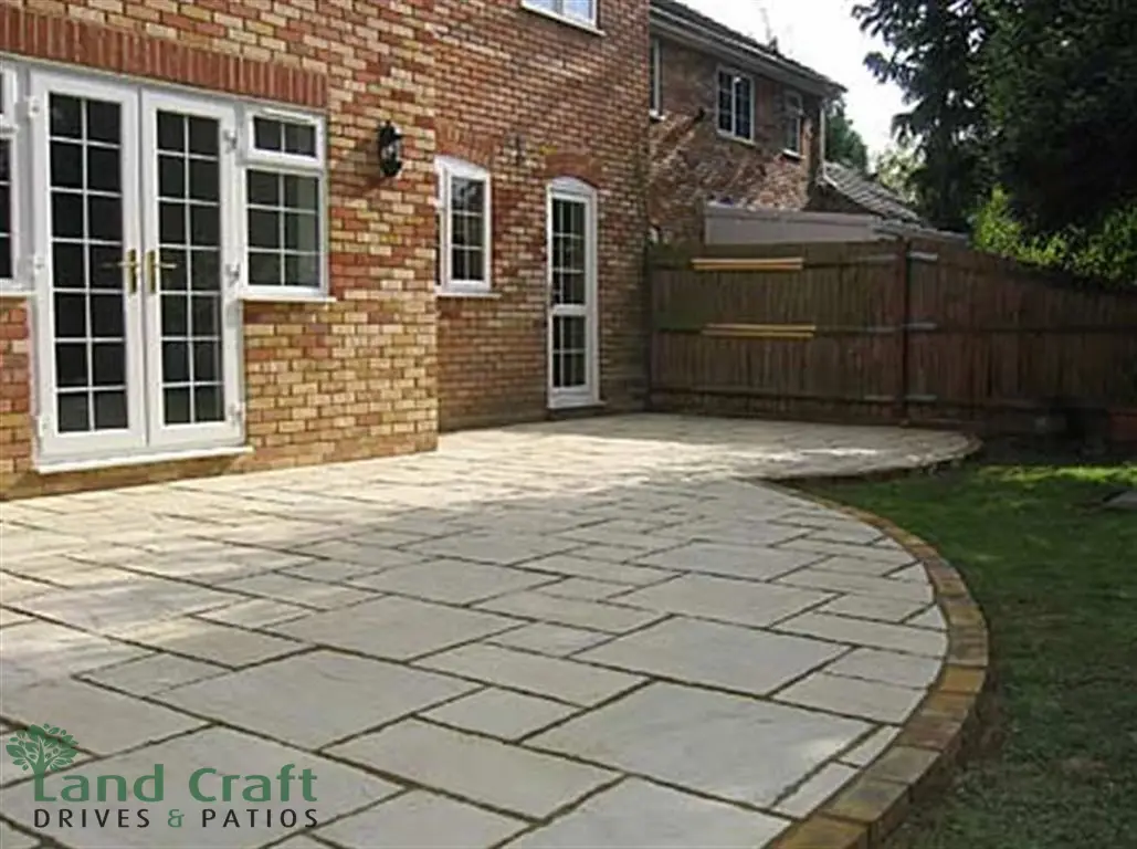 Sandstone patio with a curved edge beside a house